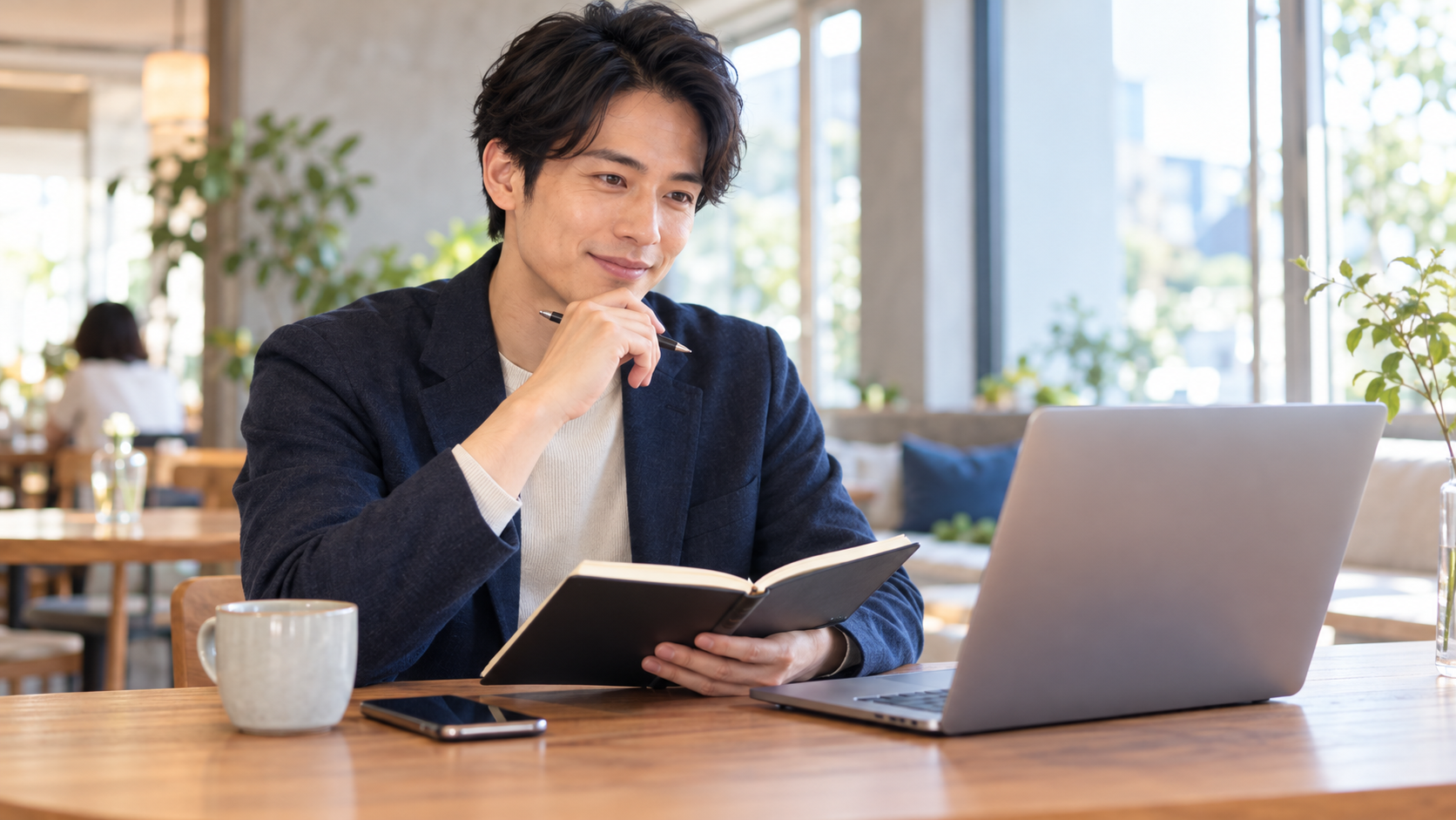 カフェでノートとパソコンを使い応募内容を整理する男性